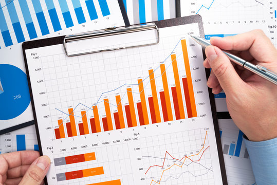 Analyzing business data. Businessman gathering statistical data. Growth charts and graphs. Pile of reports.
