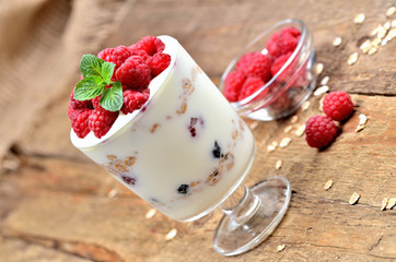 Greek yogurt with oatmeal and fresh raspberries in a glass and mint leaves