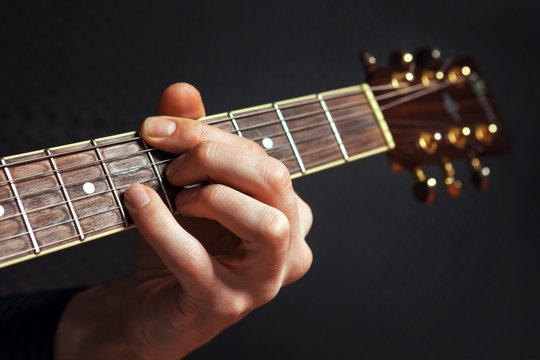 Closeup of guitarist practicing with acousic guitar.