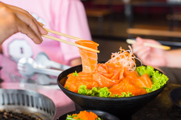 Raws salmon fillet with chopsticks on dish  in restaurant