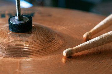 Pair of drumsticks lying on cymbal.