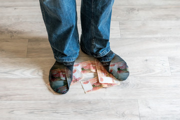 feet of a man stand on ruble banknotes