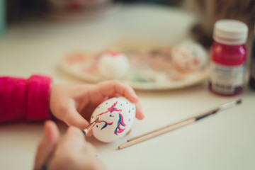 Girl painting on the easter egg at the desk