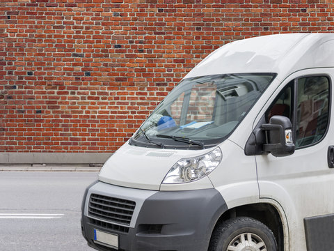 White commercial transportation and delivery van on street with red brick background