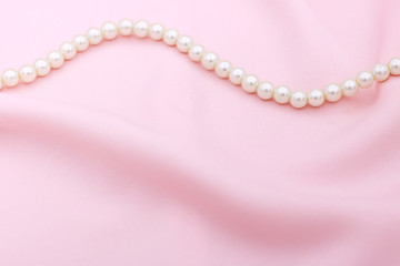 Pearl necklace on the pink fabric with copy space.