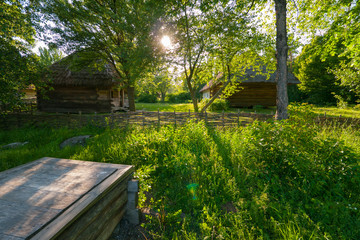Old wooden houses in the village embedded green trees and grass
