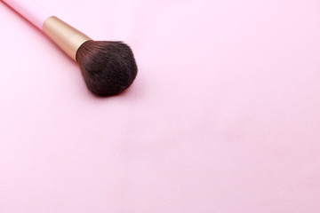 Makeup brush on the pink backfround with copy space.