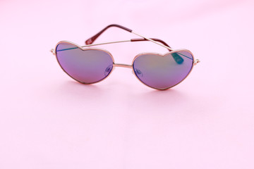 Heart sun glasses on pink background. Fashion and summer concept.