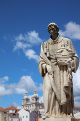 Fototapeta na wymiar Sculpture of Sao Vicente (St. Vincent of Saragossa), Lisbon's Patron Saint, with Igreja de Sao Vicente de Fora in the Background. Lisbon. Portugal