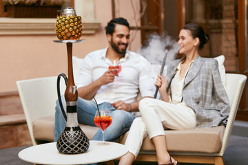 Couple Smoking Shisha With Fruit Cup In Hookah Bar