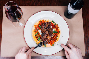 dinner of meat, a glass of red wine and a bottle, top view