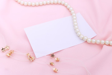 Pearl and stars necklace on the pink fabric with paper note.