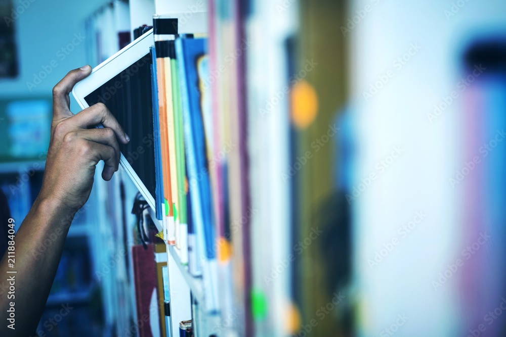 Poster hand of student keeping digital tablet in bookshelf in library
