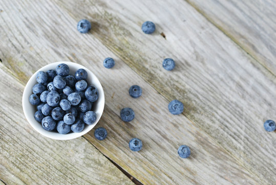 Fresh picked blueberries on white bowl, healthy summer fruits on wooden table
