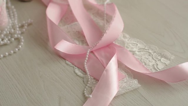Close-up of pink and white silk ribbon on white background. Slow motion.