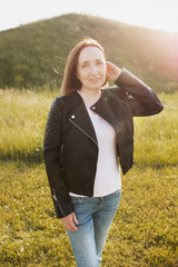 Portrait of a slim beautiful middle-aged woman posing against the backdrop of a picturesque hill on a bright summer sunny day