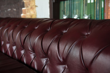 Background close-up burgundy leather sofa and bookshelf