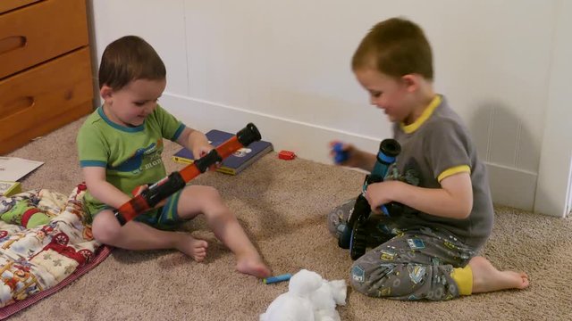 Two adorable brothers playing with nerf guns in their bedroom