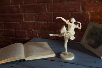 White porcelain figurine of a ballerina with an open book against