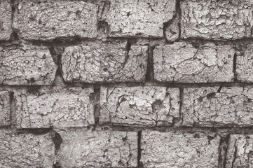 Texture of aged red brick wall painted white color with cracked weathered structure close-up