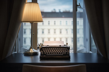 Workplace of a writer, journalist, creator. An old typewriter and a lamp on the table. Retro style....