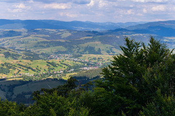 panorama of a green mountain valley with villages against a cloudy cloudy sky background