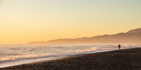 Granada, Spain; January 21, 2018: Woman walking on the beach in a golden sunset