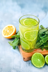 Yellow and green cocktail with lime, lemon and strawberry top view. Blue background. Copy space for text.