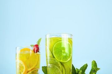 Yellow and green cocktail with lime, lemon and mint close-up view. Blue background. Copy space for text.