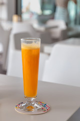 tall glass of freshly squeezed orange juice stands on a table in an open cafe