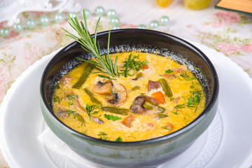 Creamy mushroom soup with root vegetables and almonds decorated with fresh parsley and rosemary.