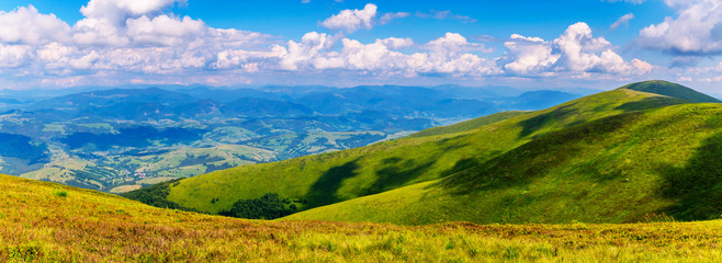 Naklejka na ściany i meble bright peaks of the Carpathians are covered with green grass, over which white fluffy clouds swim