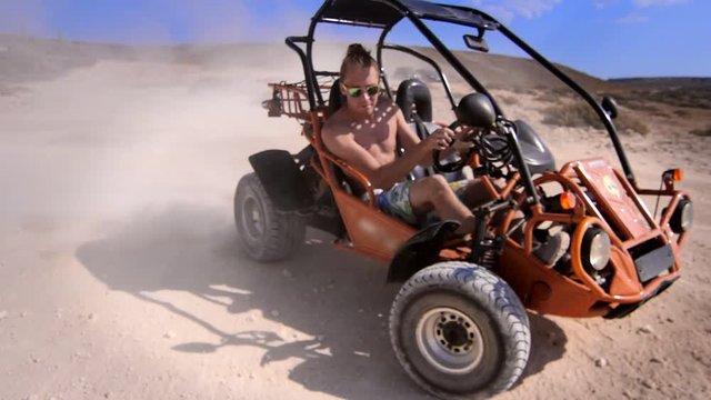 Driver man ride on sand buggy car in desert. Close up of extreme man riding on desert car around. Summer extreme. Desert racing car. Hipster man enjoy safari travel. Extreme holiday
