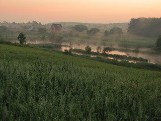 Fototapeta premium fog rising up the lake in the valley at dawn before sunrise, among the fields
