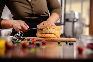 The pastry chef prepares a biscuit cake in the home kitchen or in a restaurant. The concept of the process of making cakes for restaurants, cafes and bars. on the photo the girl hands cuts a biscuit