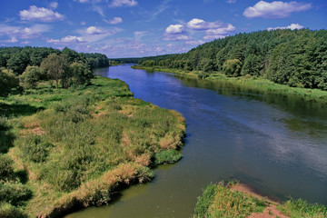 Obraz na płótnie Canvas Fast river flow with green trees on the coastal slopes against the blue sky