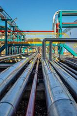 Perspective de tuyaux chromés sur fond de ciel bleu dans une usine pétrochimique
