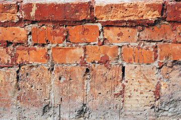 The texture of the old red brick wall with scratches and cracks