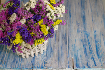 white wicker basket with multi-colored wildflowers. blue and white wooden background