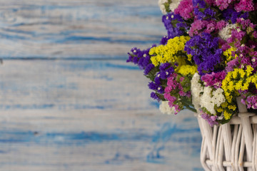 white wicker basket with multi-colored wildflowers. blue and white wooden background