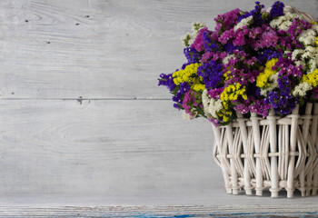 defocus. white wooden basket with colored wildflowers. wooden white \ blue background