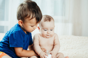 brother communicates and plays with her younger sister six months old