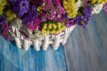 white wicker basket with multi-colored wildflowers. blue and white wooden background