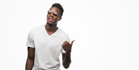 Young african american man wearing sunglasses pointing with hand and finger up with happy face smiling