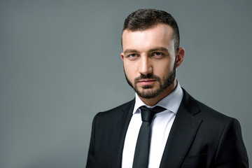 portrait of handsome businessman looking at camera isolated on grey