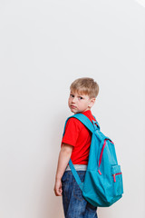 boy in the red t-shirt and backpack looking at camera on white background