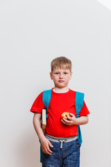 first grader in the red t-shirt and backpack looking at camera on white background