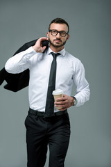 handsome businessman walking with coffee to go isolated on grey