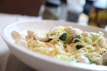 alfredo spaghetti broccoli chicken white sauce in restaurant background
