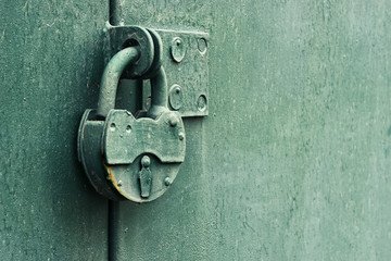 Old  rusty padlock  on an iron green  fence
